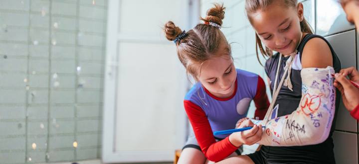 Girls signing a friend's cast in gymnastics practice.