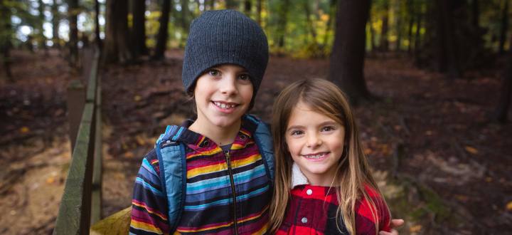 Younng boy and girl standing in the woods
