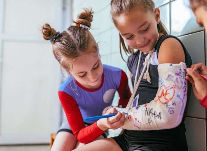 Young girl signing friend's cast at gymnastics practice