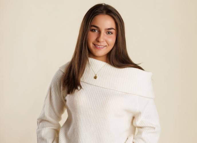 Young woman with long brown hair and cream sweater