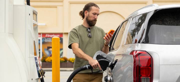 Man pumping gas while looking at phone