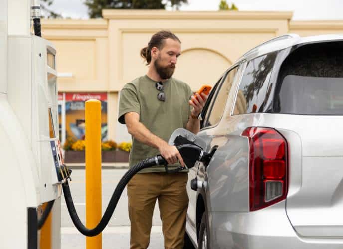 Man pumping gas while looking at phone